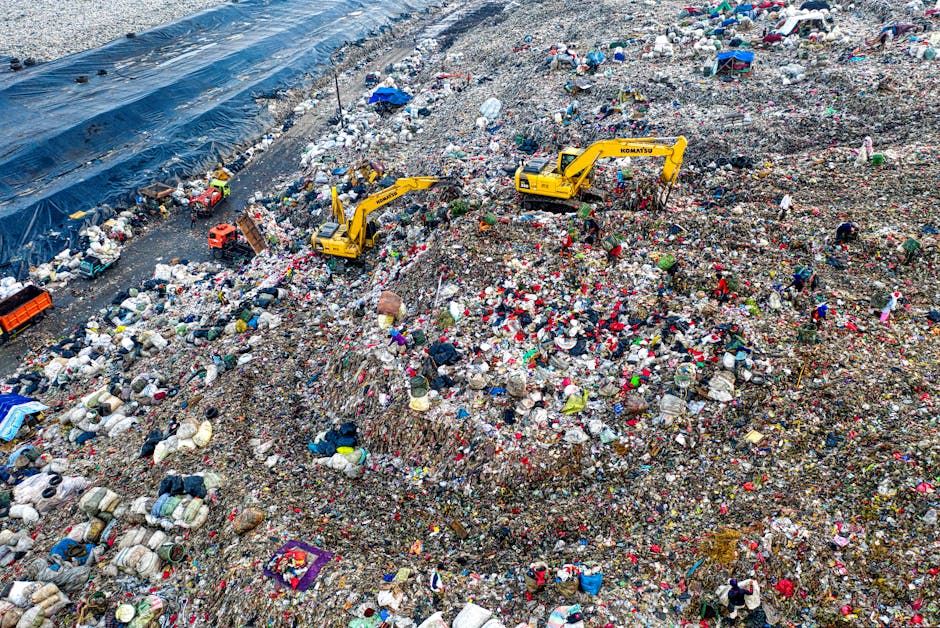The image depicts a large accumulation of mixed waste and rubbish, including plastic bags, cardboard, broken furniture, and miscellaneous debris, spread across an open area at the base of tall urban h